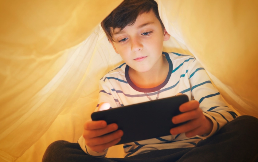 child hiding under sheets using an ipad withdrawn signs of anxiety in child