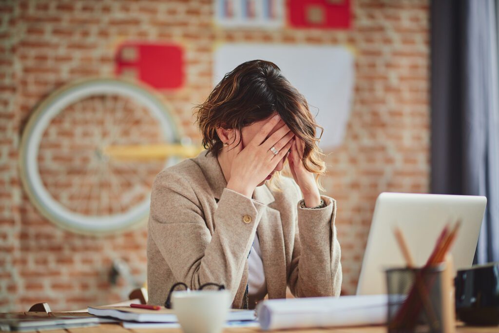 woman working with head in hands headache stress anxiety